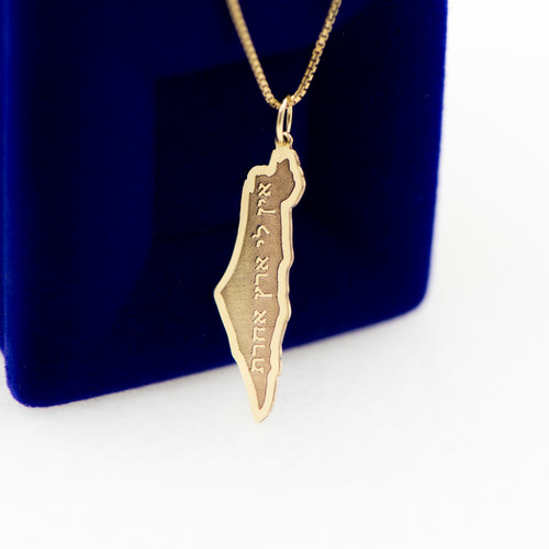 תליון זהב מפת ישראל עם הטבעה "ארץ אל אשר אהבתי", על קופסת תכשיטים כחולה.